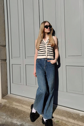 a lady in a striped knitted vest and a pair of wide leg jeans